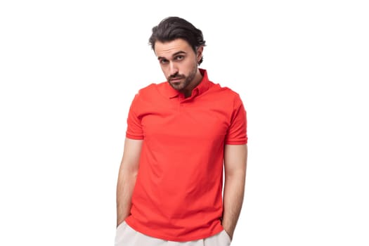 young funny caucasian brunette man with beard dressed in casual red t-shirt on studio background with copy space.
