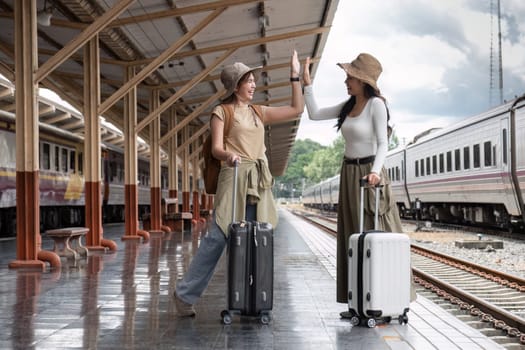 Young woman holding a suitcase waiting for a train at the train station while traveling on a weekend trip..