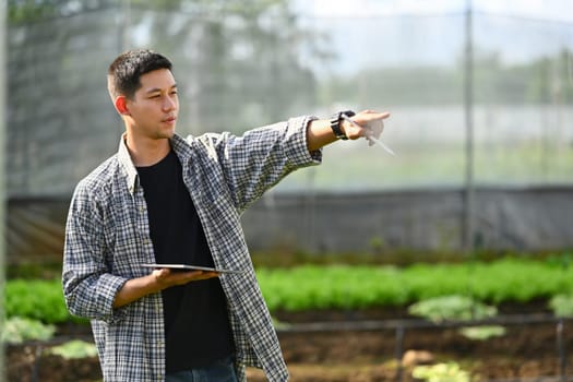 Farmer checking organic vegetable and recording farming data on digital tablet. Innovation and smart farm system concept.