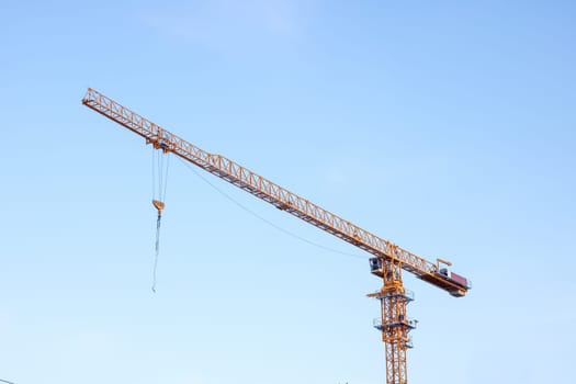 Construction crane on bright blue sky background close up