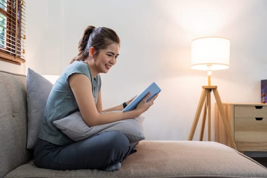 Happy young woman read book on sofa at home. Lifestyle freelance relax in living room. Lifestyle Concept.