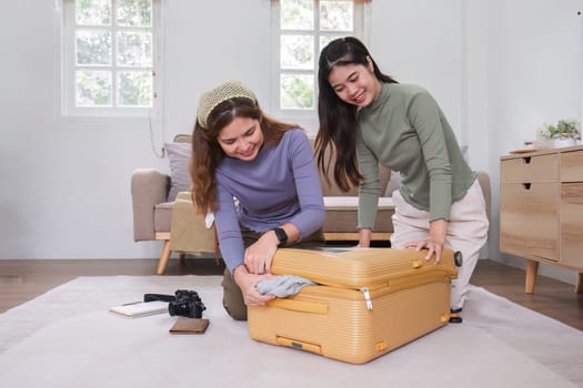 Two Asian female friends pack their suitcases and plan a vacation. Before going on vacation together.