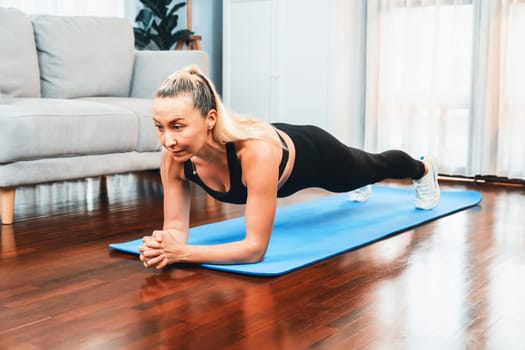 Athletic and sporty senior woman planking on fitness exercising mat at home exercise as concept of healthy fit body lifestyle after retirement. Clout