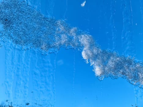 Frozen ice on a window with a blue sky background
