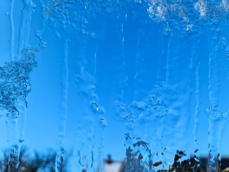 Frozen ice on a window with a blue sky background