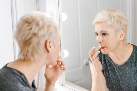 Beautiful woman with short haircut looking in mirror at her home