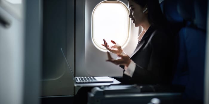 Successful Asian business woman, Business woman working in airplane cabin during flight on laptop computer.
