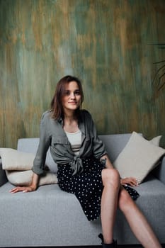Woman on grey sofa with pillows in room