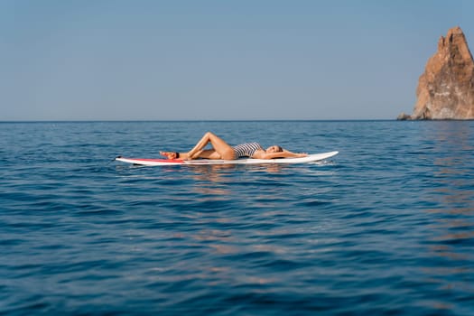 Sporty girl on a glanders surfboard in the sea on a sunny summer day. Summer activities by the sea.