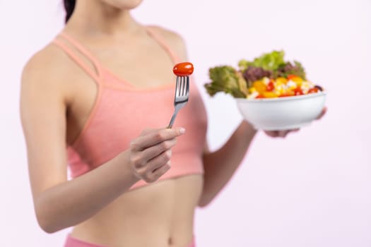 Young sporty Asian woman in sportswear holding salad bowl fill with vibrant of fruit and vegetable. Natural youthful and fit body lifestyle with balance nutrition on isolated background. Vigorous