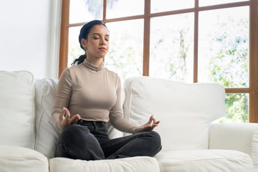 Young African American woman practice crucial mindful meditation at home living room for improving mental health strength and peaceful beautiful living