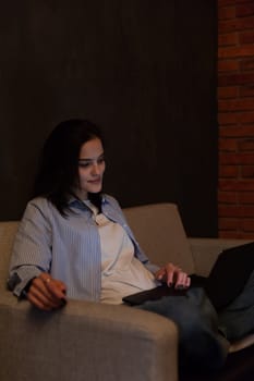 Woman sitting on sofa with computer chatting online