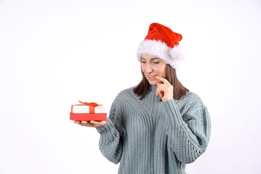 Portrait happy woman in Santa hat and sweater holding gift box on white background