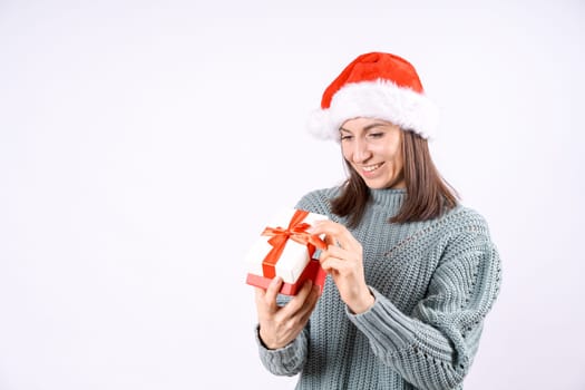 Portrait happy woman in Santa hat and sweater holding gift box on white background