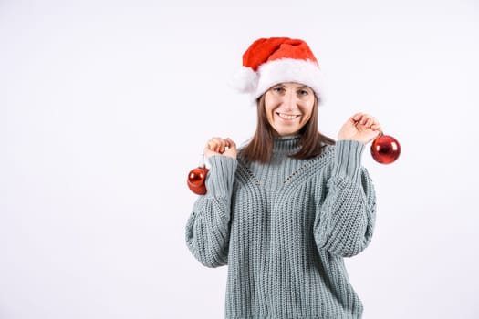 Portrait happy woman in santa hat and sweater holding red balls for Christmas tree on a white background