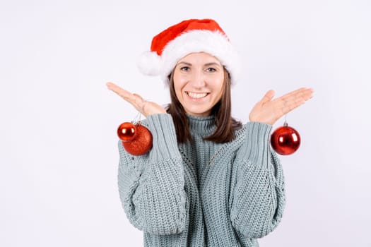 Portrait happy woman in santa hat and sweater holding red balls for Christmas tree on a white background