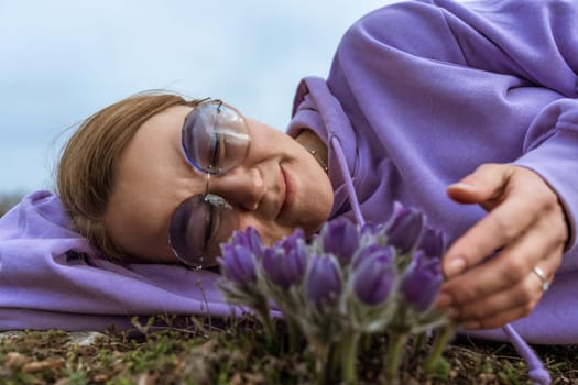 Dream grass woman spring flower. Woman lies on the ground and hugs flowers pasqueflower or Pulsatilla Grandis flowers.