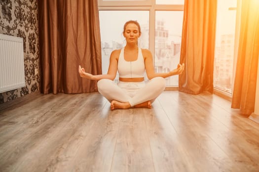 Young woman meditating at home. Girl practicing yoga in class. Relaxation at home, body care, balance, healthy lifestyle, meditation, mindfulness, recreation, workout, fitness, training concept.