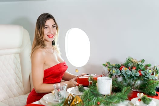 woman sits in private jet by illuminator, decorated for Christmas, New Year's Eve flight, holiday and travel concept