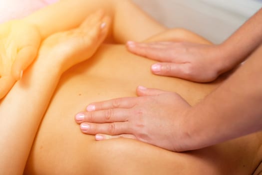 Top view of hands massaging female abdomen.Therapist applying pressure on belly. Woman receiving massage at spa salon.