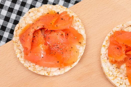 Tasty Rice Cake Sandwiches with Fresh Salmon Slices on Cutting Board - Top View. Easy Breakfast and Diet Food. Crispbread with Red Fish. Healthy Dietary Snack