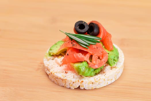 Rice Cake Sandwich with Fresh Salmon, Avocado and Olives on Bamboo Cutting Board. Easy Breakfast. Diet Food. Quick and Healthy Sandwiches. Crispbread with Tasty Filling. Healthy Dietary Snack