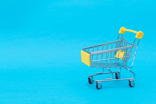 Empty Yellow Shopping Cart on Blue Background. Shopping, Trade and Market Concept