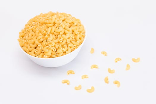 Uncooked Chifferi Rigati Pasta in White Cup Isolated on White Background. Fat and Unhealthy Food. Scattered Classic Dry Macaroni. Italian Culture and Cuisine. Raw Pasta - Isolation