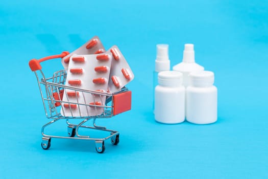 Buying Medicines. Expensive Medicine and Inflation Concept: Pills and Capsules in Shopping Cart on Blue Background. Global Pharmaceutical Industry and Big Pharma. Ordering Pharmaceutical Products