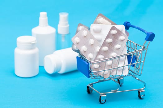 Buying Medicines. Expensive Medicine and Inflation Concept: Pills and Capsules in Shopping Cart on Blue Background. Global Pharmaceutical Industry and Big Pharma. Ordering Pharmaceutical Products
