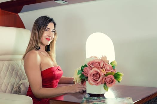 woman sits in private jet by illuminator, decorated for Christmas, New Year's Eve flight, holiday and travel concept