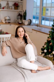 Cute woman using smartphone to call family on Christmas Eve. Talks to relatives on the phone to celebrate the holiday remotely. Communication for adults