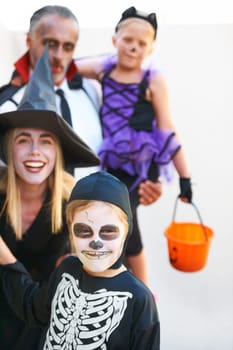Portrait, halloween and a family in costume for the tradition of trick or treat or holiday celebration. Mother, father and kids at a door in fantasy clothes for dress up on allhallows eve together.