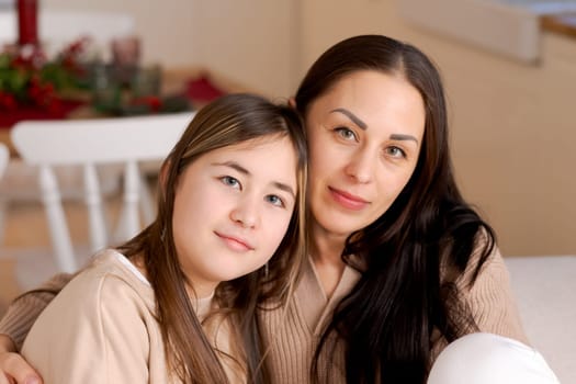 Mom and daughter sitting on couch cuddled together waiting for Christmas to arrive