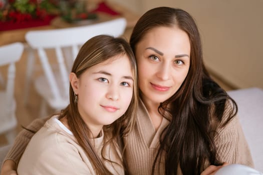 Mom and daughter sitting on couch cuddled together waiting for Christmas to arrive