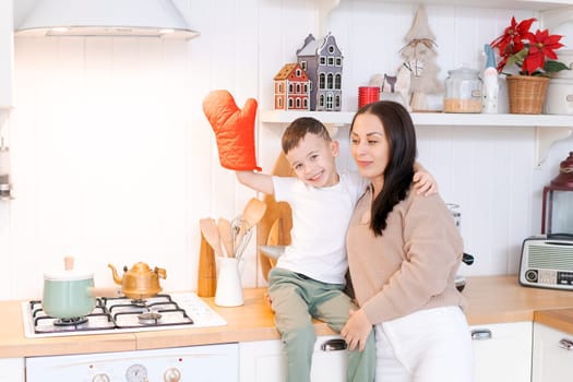 Fun mom and son playing in kitchen, happy spending time on Christmas Eve and New Year's Eve