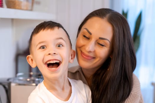 Fun mom and son playing in kitchen, happy spending time on Christmas Eve and New Year's Eve