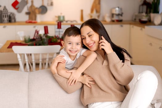 Happy woman sits on couch holding cell phone, using cellular technology, shopping online, texting, relaxing on the couch in the cozy living room of her home.