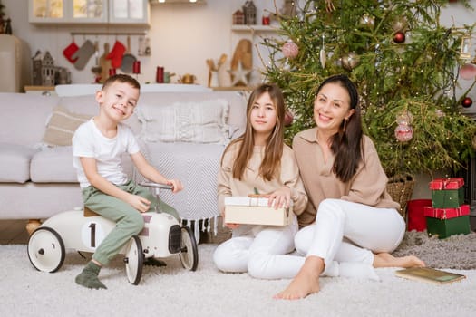 Happy family in decorated house at Christmas sitting on floor against couch and Christmas tree. Selective focus