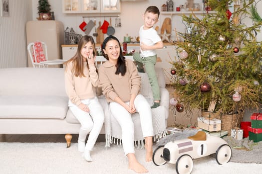 Family spends time together during Christmas holidays in decorated house. Mother and her two children hug each other as they prepare for holiday. Selective focus