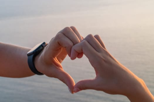 Hands heart sea sanset. Hands forming a heart shape made against the sun sky of a sunrise or sunset on a beach.