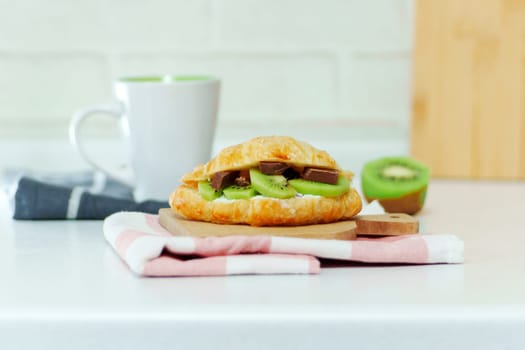 Croissant stuffed with curd cheese, with kiwi ricotta and chocolate. Homemade croissants.