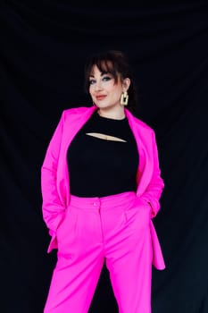 Woman in bright suit posing on black background in studio