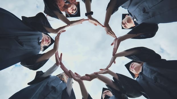 College graduates make a circle of their hands