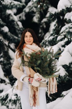 A girl in a winter forest with a bouquet of fir branches. Snowy winter.