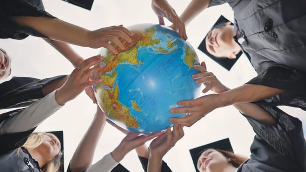 Graduating students twirl a geographic globe of the world in their hands