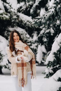 Portrait of a girl with long hair in mittens in a winter forest . Snowy winter.