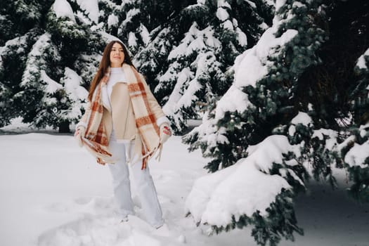 Portrait of a girl with long hair in mittens in a winter forest . Snowy winter.