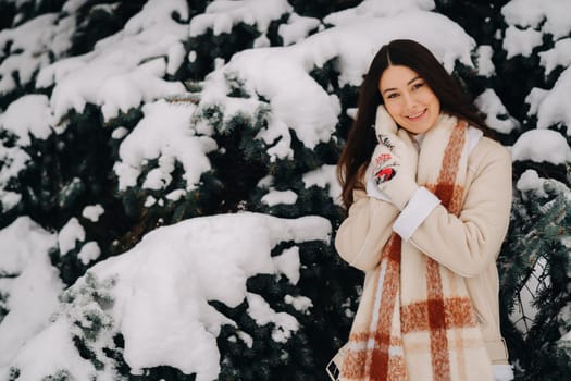 Portrait of a girl with long hair in mittens in a winter forest . Snowy winter.