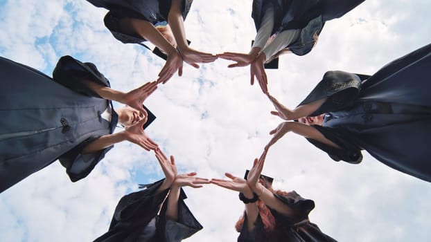 College graduates make a circle of their hands